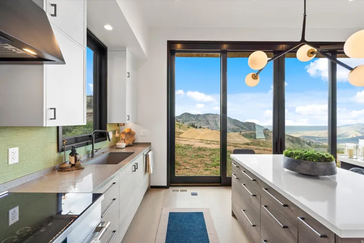 Modern kitchen with white cabinetry, a large center island with a white countertop, and expansive sliding glass doors