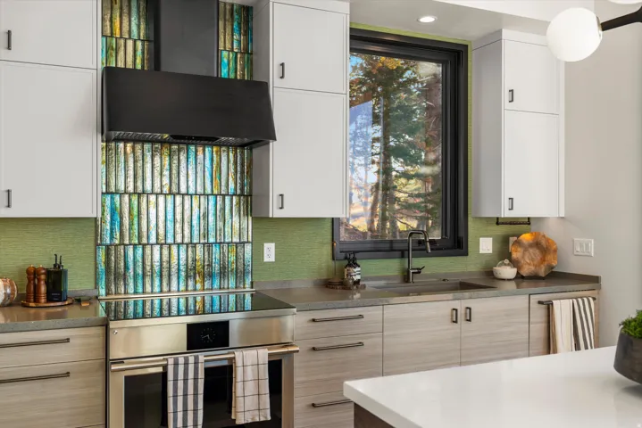 Modern kitchen featuring stainless steel appliances, stone countertops, and a full-height tile backsplash