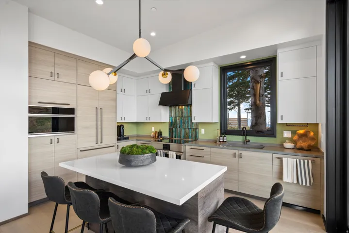 Modern kitchen with built-in appliances, a central island, and a geometric chandelier