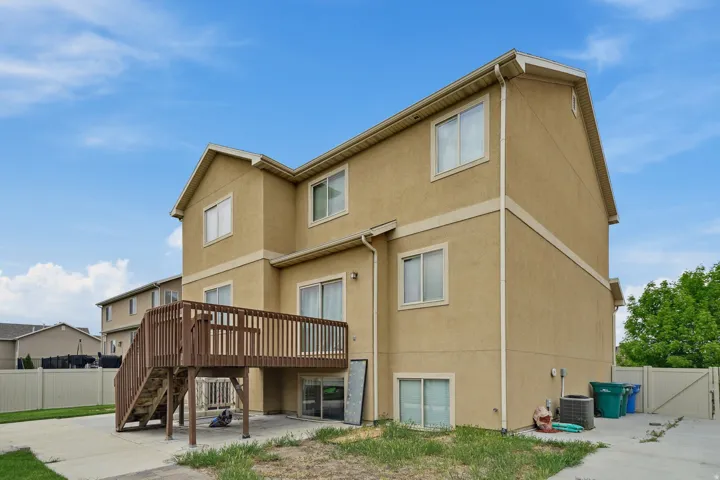 Multi-level stucco exterior with a wooden deck and staircase