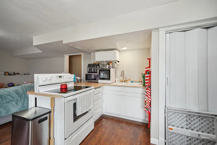 Compact kitchen featuring white cabinetry, a single basin sink, and wood-finish flooring