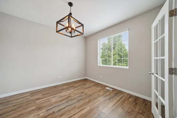 Neutral tone walls, wood-finish flooring, and a modern geometric light fixture