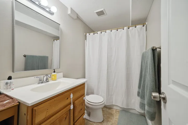 Vanity with wood-finish cabinetry, white countertop, and integrated sink