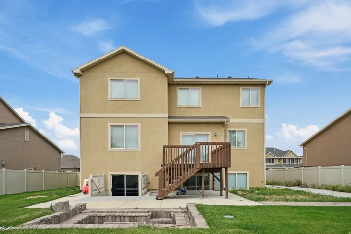 Stucco exterior with multiple windows, leading to a wood deck and staircase