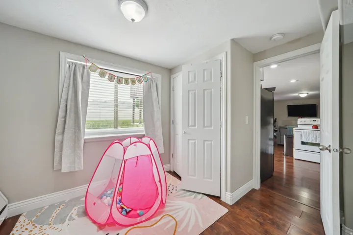 Window with blinds and drapes, flush mount ceiling lighting, wood-finish flooring, and white trim throughout