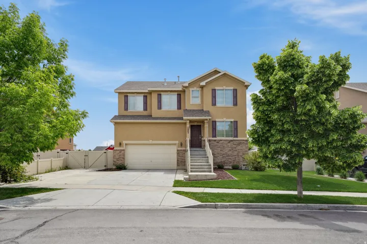 Two-story residence featuring a stucco exterior with stone accents, an attached garage, and a concrete driveway