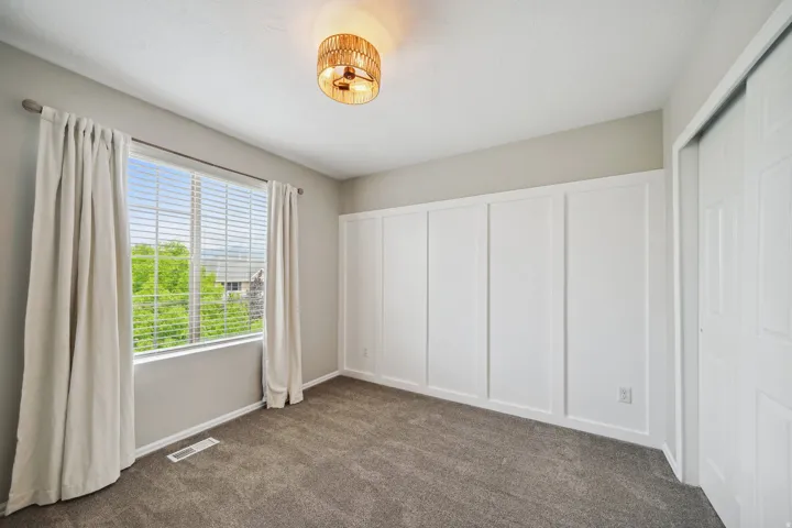 Textured gray carpeting, board and batten wall detailing, and a woven ceiling light fixture