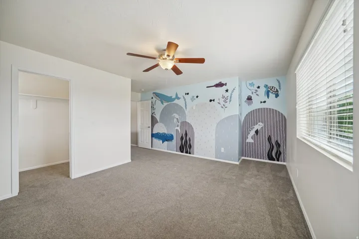 Carpeted flooring, ceiling fan with integrated lighting, window with horizontal blinds, built-in open closet, and white interior door