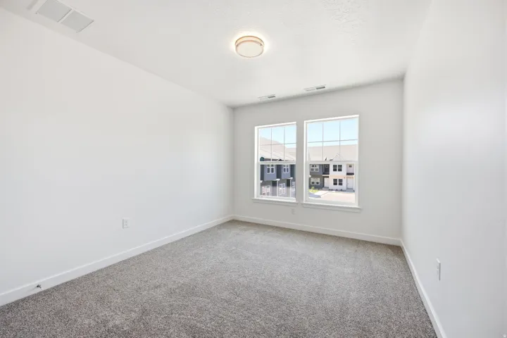 Carpeted flooring with a neutral finish, white painted walls, and two large windows with grid patterns