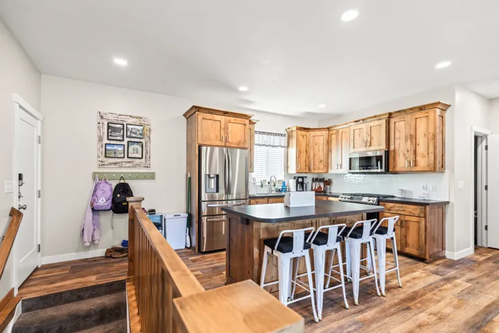 Chef's kitchen featuring custom wood cabinetry, stainless steel appliances including a French-door refrigerator and built-in microwave, black granite countertops, and a center island with seating for multiple guests