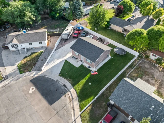 Manicured lawn, paved driveway, white privacy fencing, and a flag pole