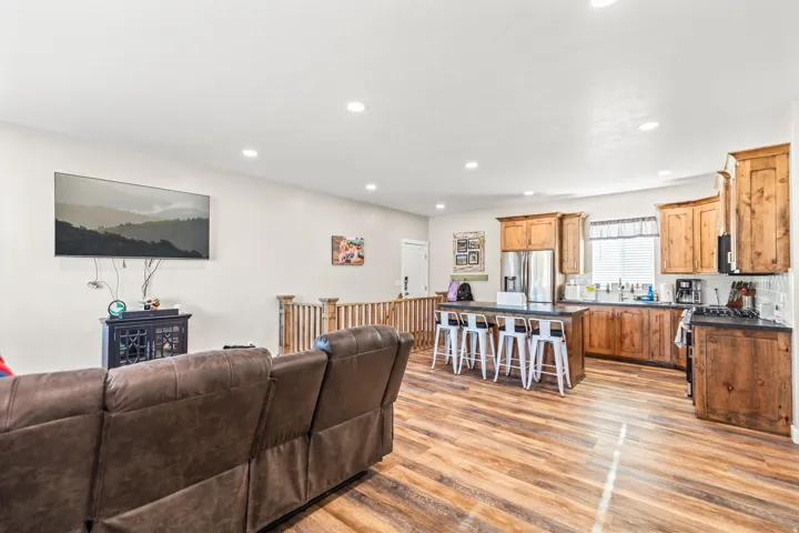 Open-concept living area featuring wood-finish flooring, recessed lighting, and a kitchen with stainless steel appliances