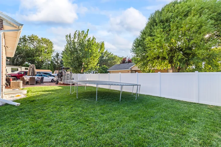 Expansive green lawn with a white privacy fence and a brick exterior
