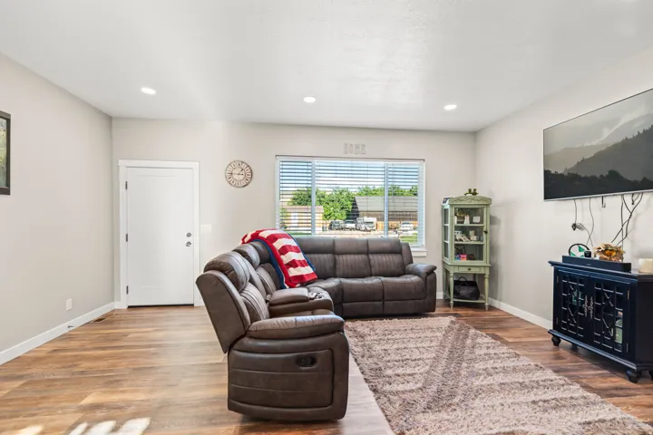 Recessed lighting, wood-finish flooring, white trim, and a window with blinds