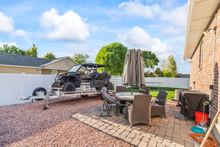 Brick exterior with a paved patio, gravel area, and white privacy fencing