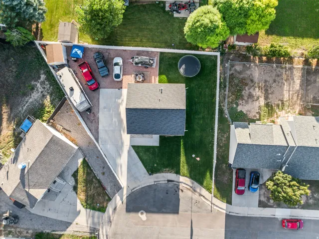 Large gravel parking area, white privacy fencing, manicured lawn, paved driveway, and established trees