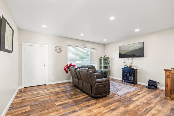 Recessed lighting, wood-finish flooring, white paneled door, and horizontal window blinds