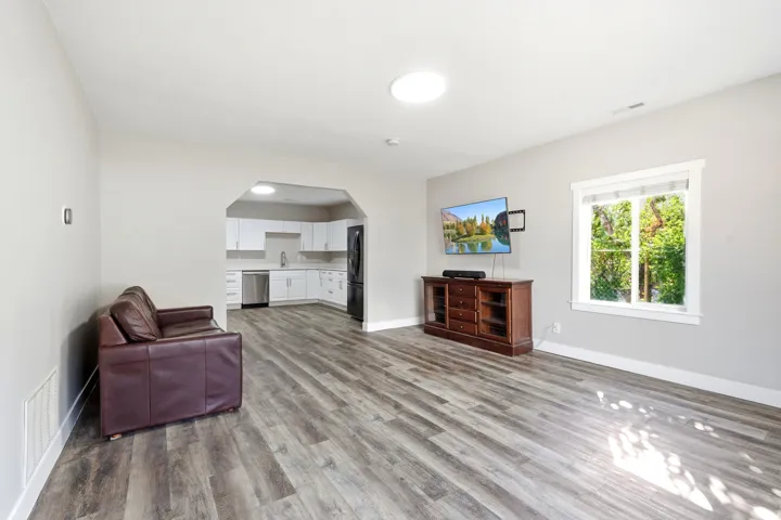 Spacious common area featuring wood-finish flooring and an arched entryway to the kitchen