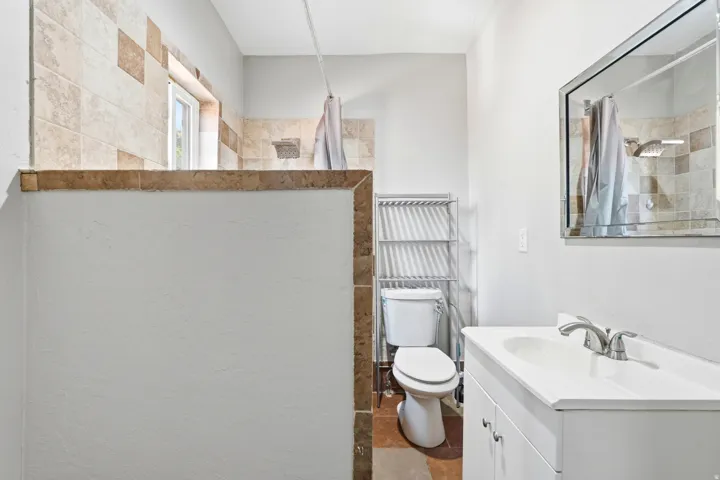Vanity with integrated sink, brushed nickel faucet, and beveled mirror