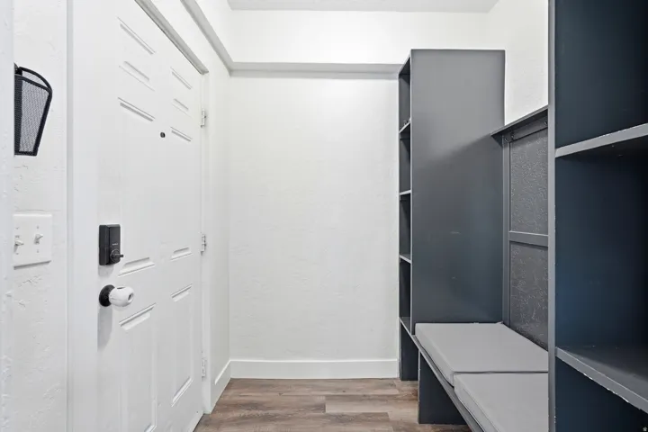 Entryway featuring a paneled door with smart lock, wood-finish flooring, and built-in shelving with bench seating