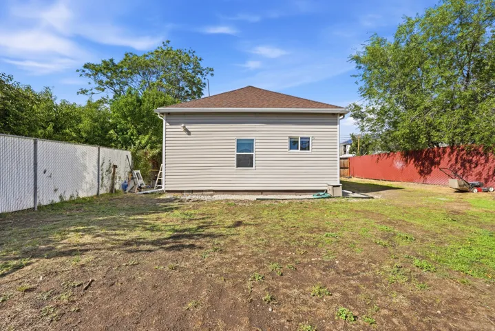 Expansive rear yard with a chain-link fence and detached structure featuring horizontal siding and a shingle roof