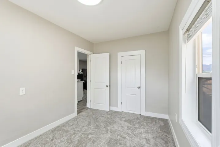 Neutral wall paint, white trim, gray carpet, white interior door, and a white framed window