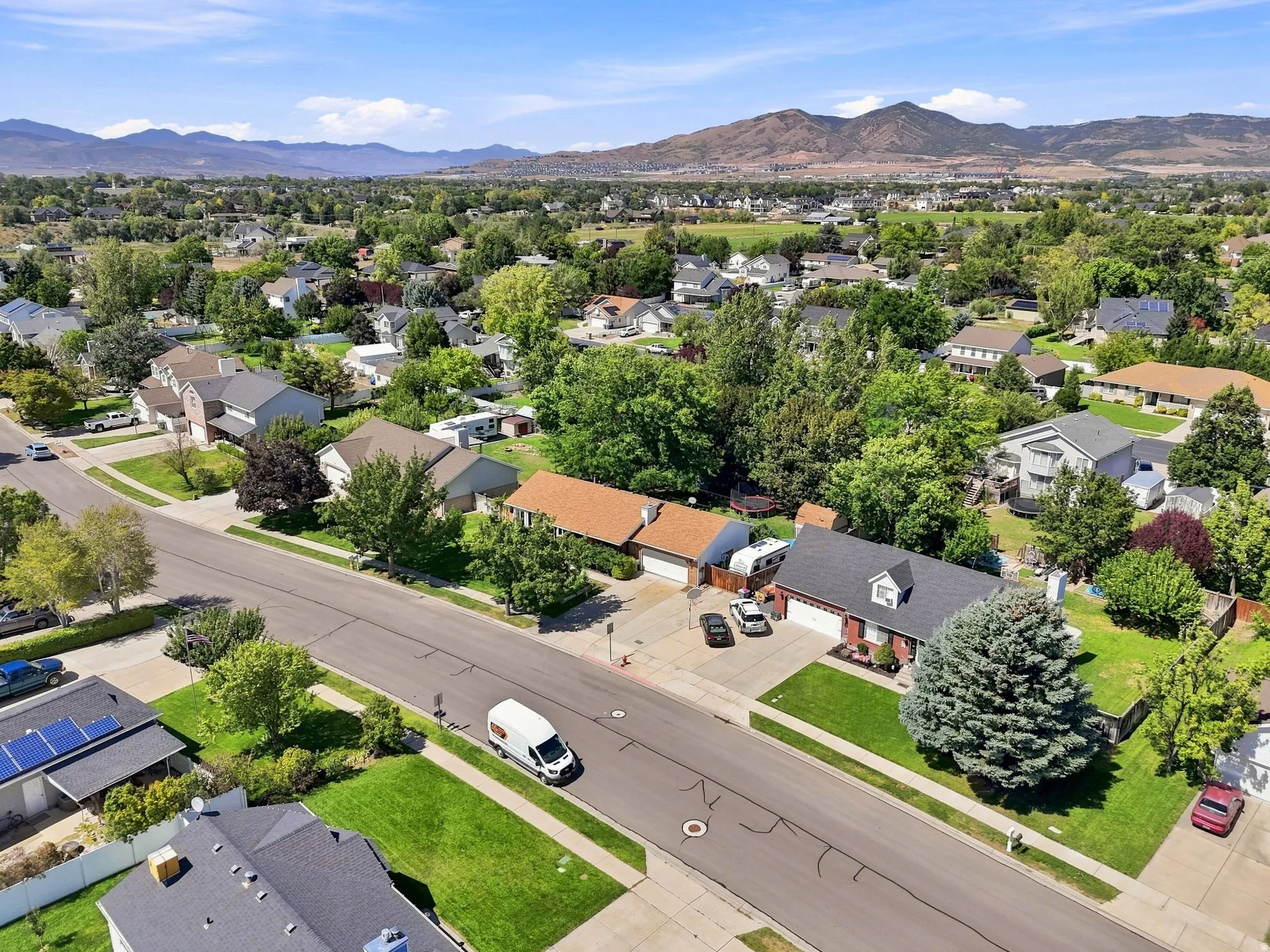 Residential neighborhood featuring mature trees and mountain scenery