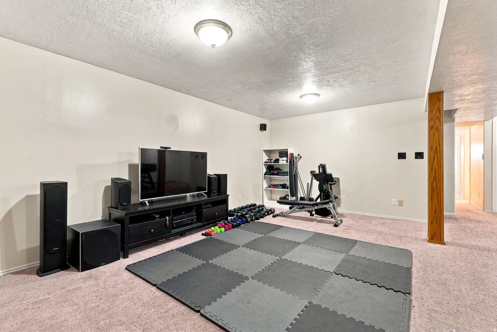 Recessed lighting illuminates the space, featuring a built-in media console and durable carpet flooring