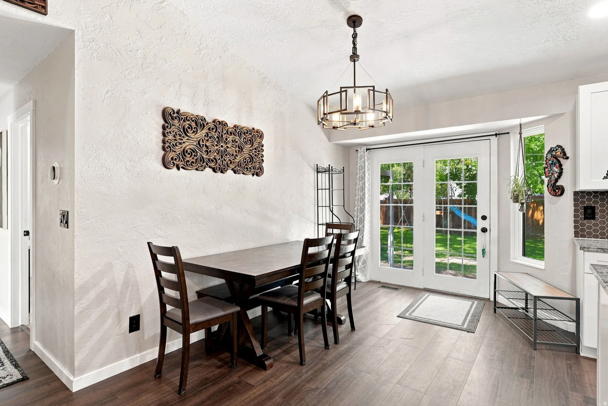 Dark wood-finish flooring, vaulted ceiling, contemporary chandelier, French doors, and bay window