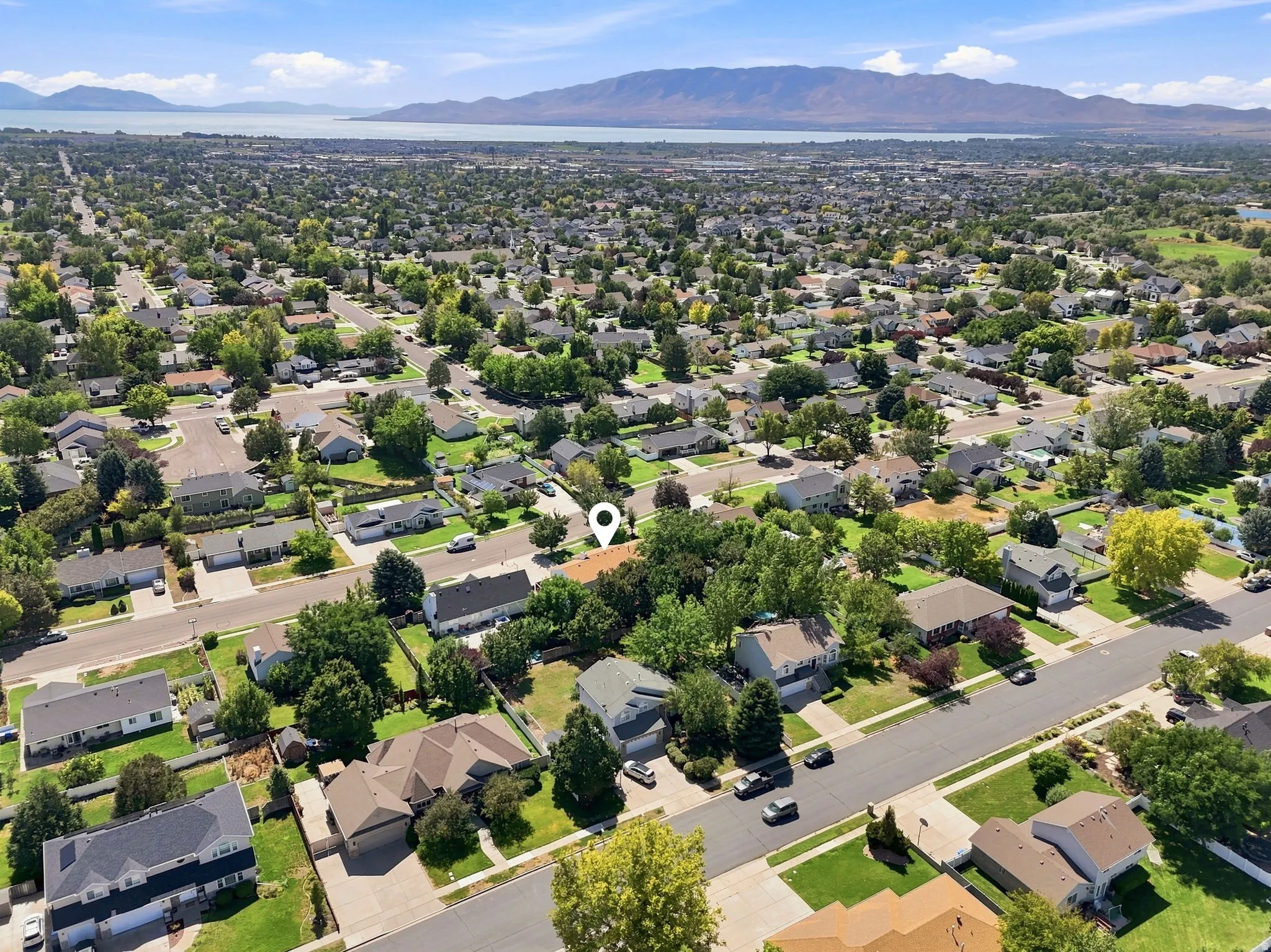 Residential neighborhood with mature trees, established properties, and a distant body of water with mountain backdrop