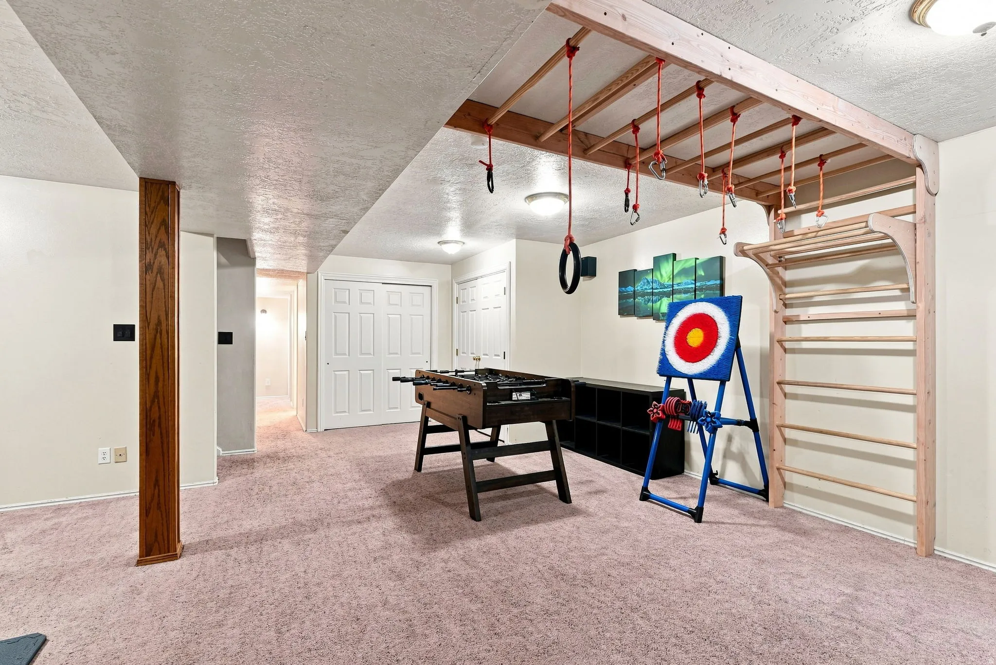 Finished basement featuring a custom ceiling-mounted climbing structure and light pink carpet