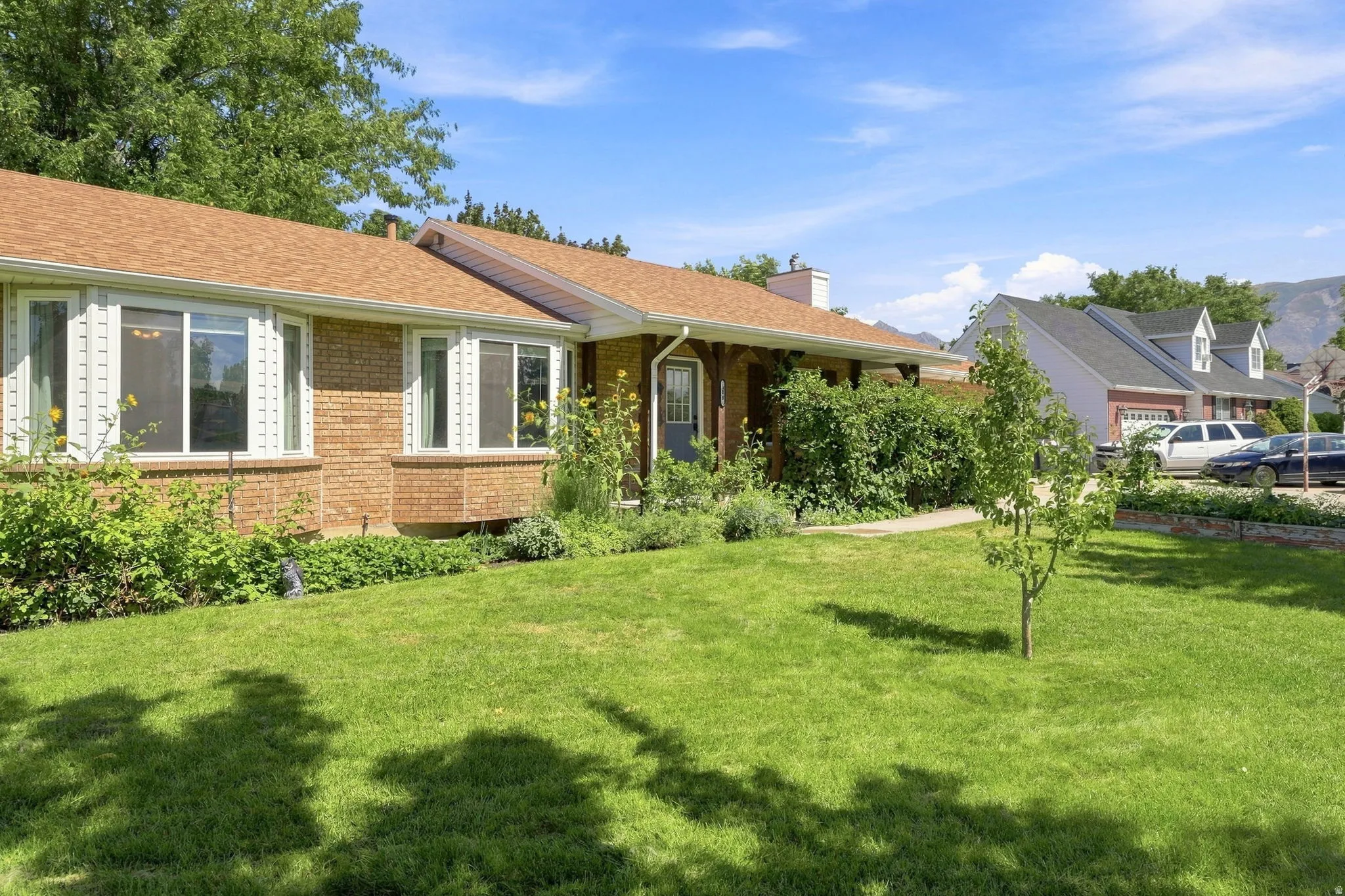 Brick exterior with multiple bay windows, a gabled roof, and established landscaping