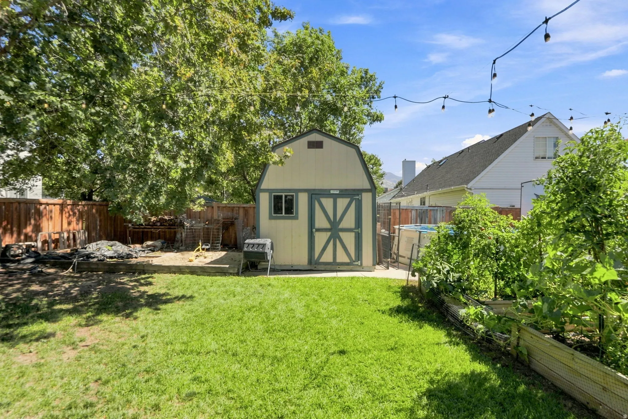 Expansive backyard featuring a green lawn, dedicated gardening beds, and a storage shed