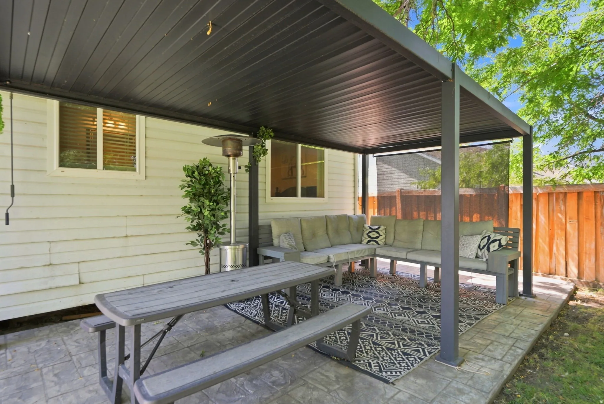 Covered patio featuring a solid roof structure, stamped concrete flooring, and a privacy screen