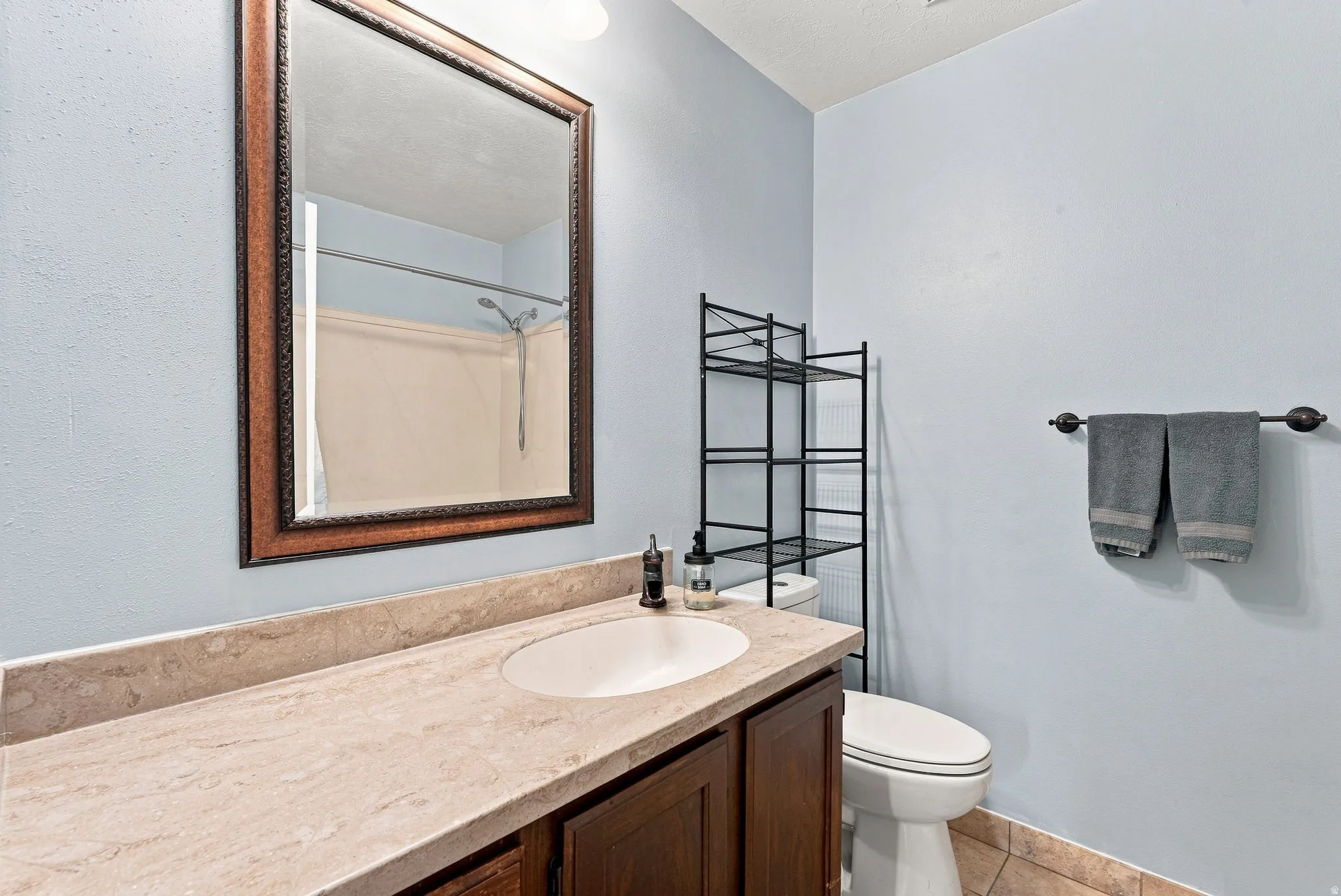 Bathroom featuring a vanity with a light-toned countertop, an integrated sink, and wood-finish cabinetry