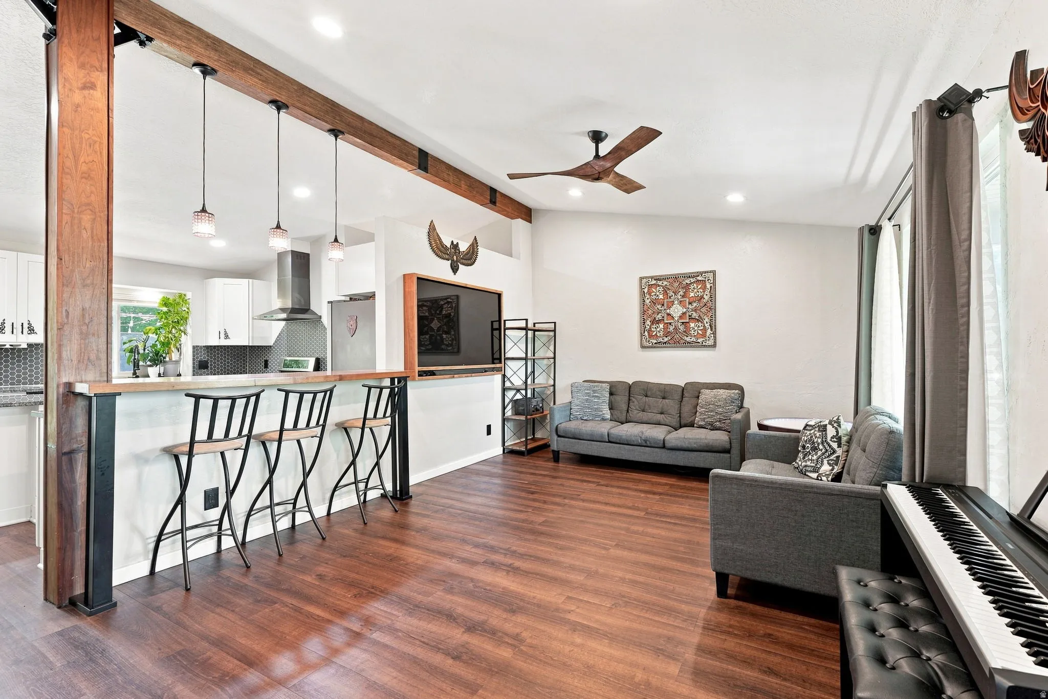Wood-finish flooring throughout, with a wood-accented structural beam and coordinating ceiling fan