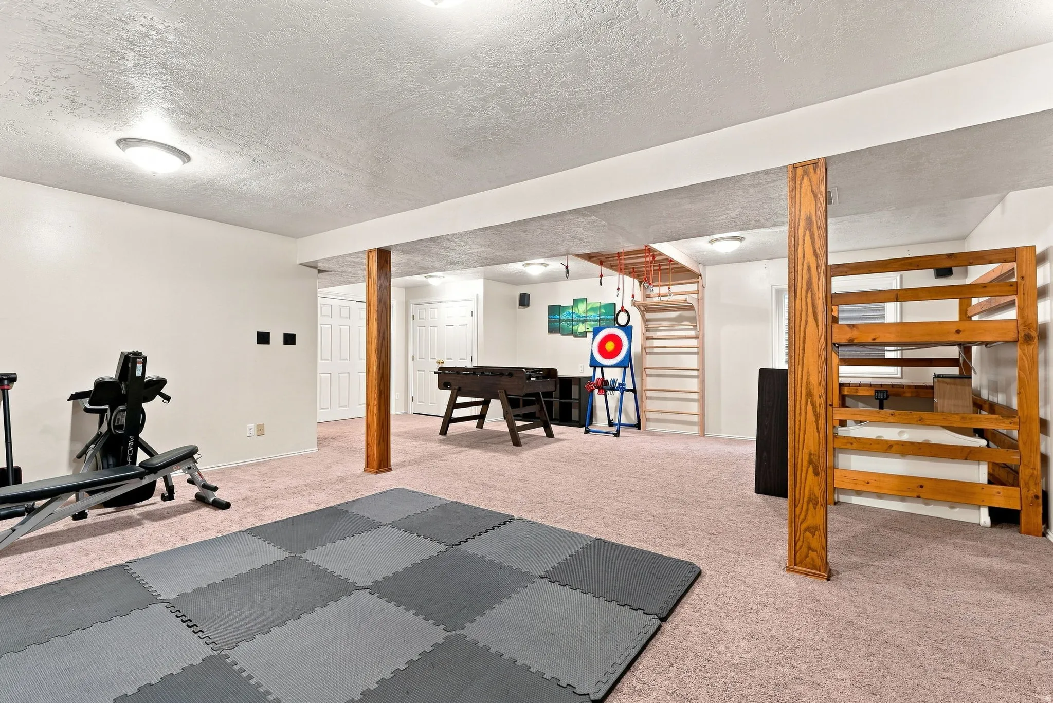 Spacious finished room with carpeted flooring, recessed lighting, and exposed wood support columns