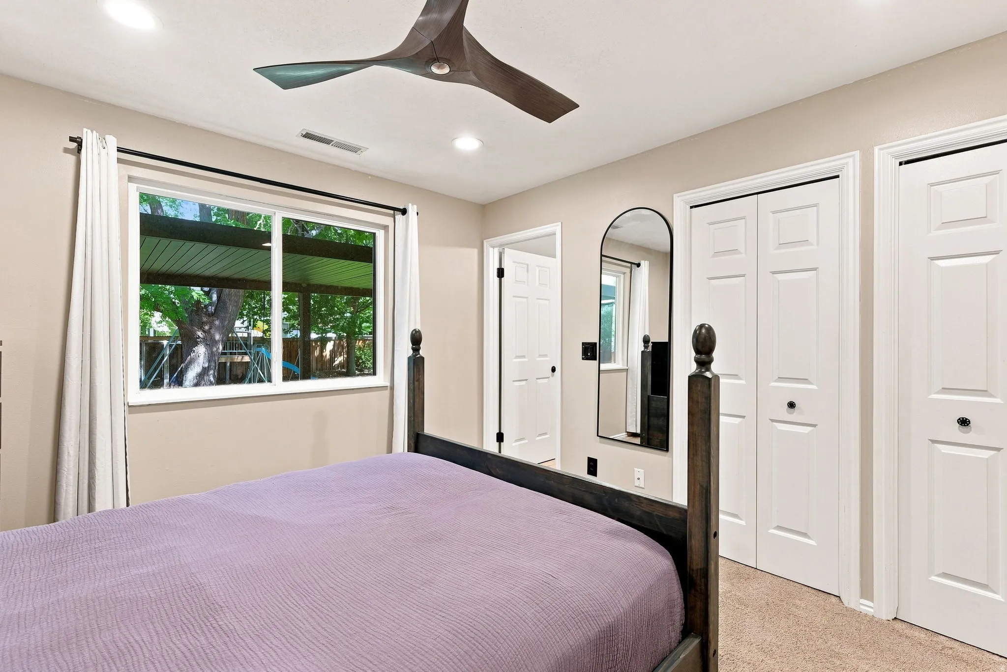 Recessed ceiling lighting, modern ceiling fan, white trim window, and two paneled bifold closet doors