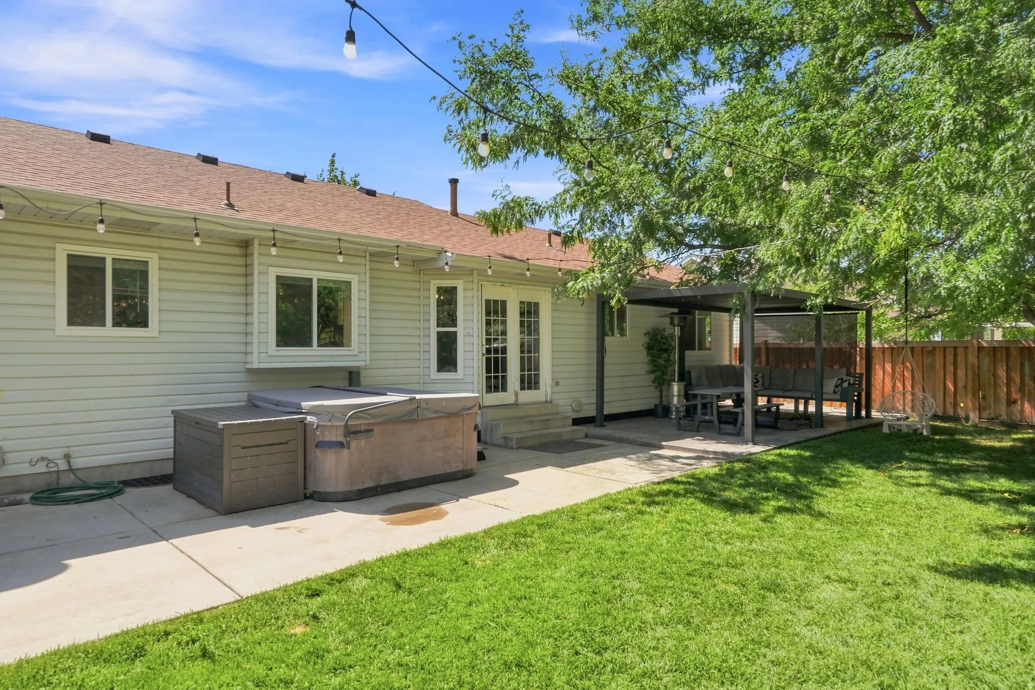 Expansive backyard featuring a concrete patio, a covered pergola, and a wooden fence