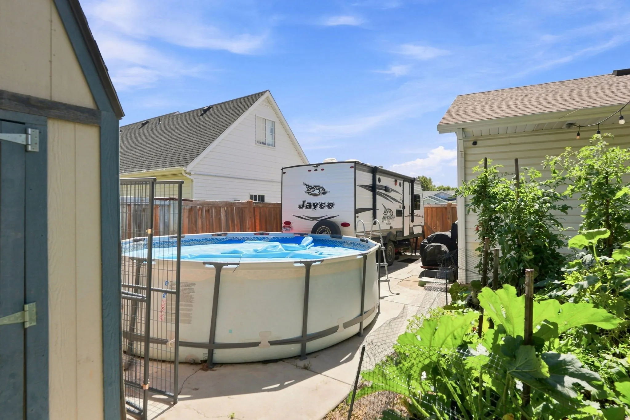 Rear yard featuring an above-ground pool, concrete patio, and garden area