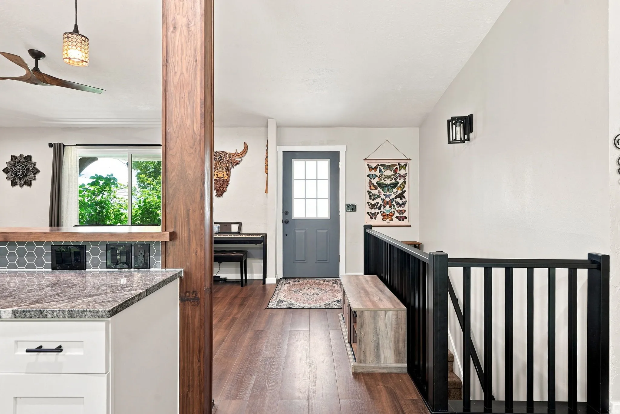 Wood-finish flooring throughout, featuring a kitchen peninsula with a stone countertop and hexagonal tile backsplash