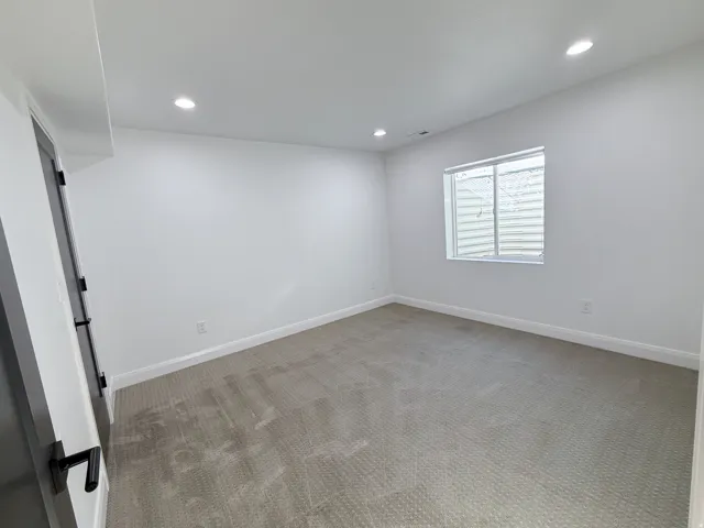 Recessed lighting illuminates this room, featuring light gray carpeting and a white trim
