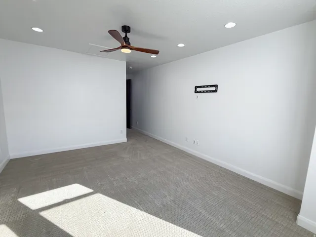 Recessed lighting, ceiling fan with integrated light, light-toned carpeting, and a wall-mounted bracket