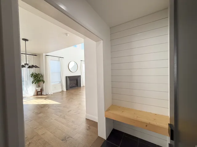 Entryway with shiplap accent wall, built-in wooden bench, and dark tile flooring