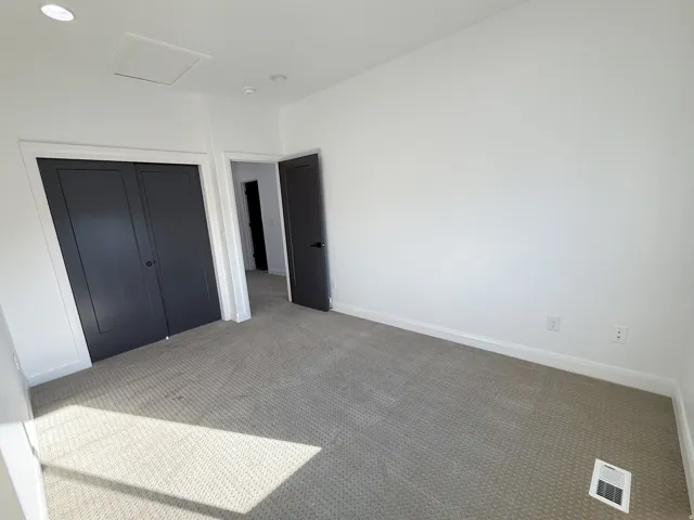 Neutral carpet flooring, white walls, recessed ceiling lighting, and solid panel doors