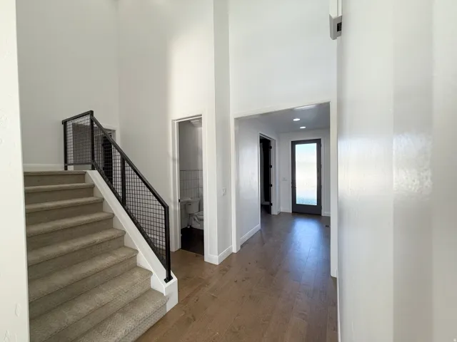Open concept entry with wood-finish flooring, recessed lighting, and a modern staircase featuring black metal railings