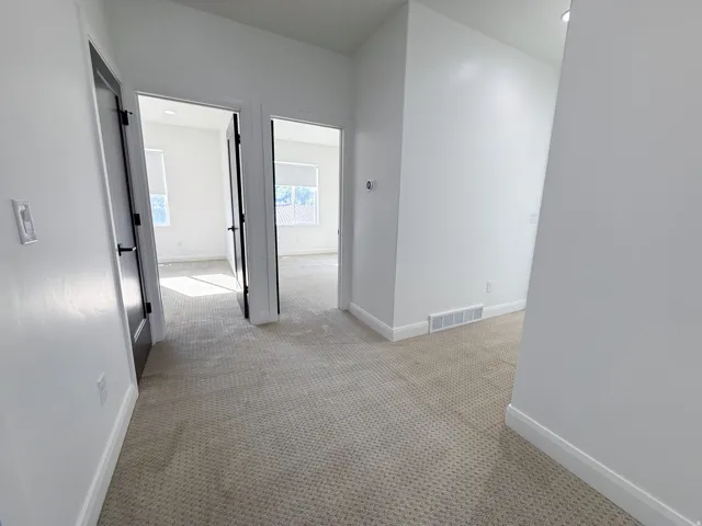 Hallway with light-toned carpeting and white walls