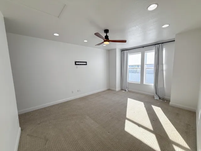 Recessed lighting, ceiling fan, carpeting, multiple windows, and a wall-mounted bracket