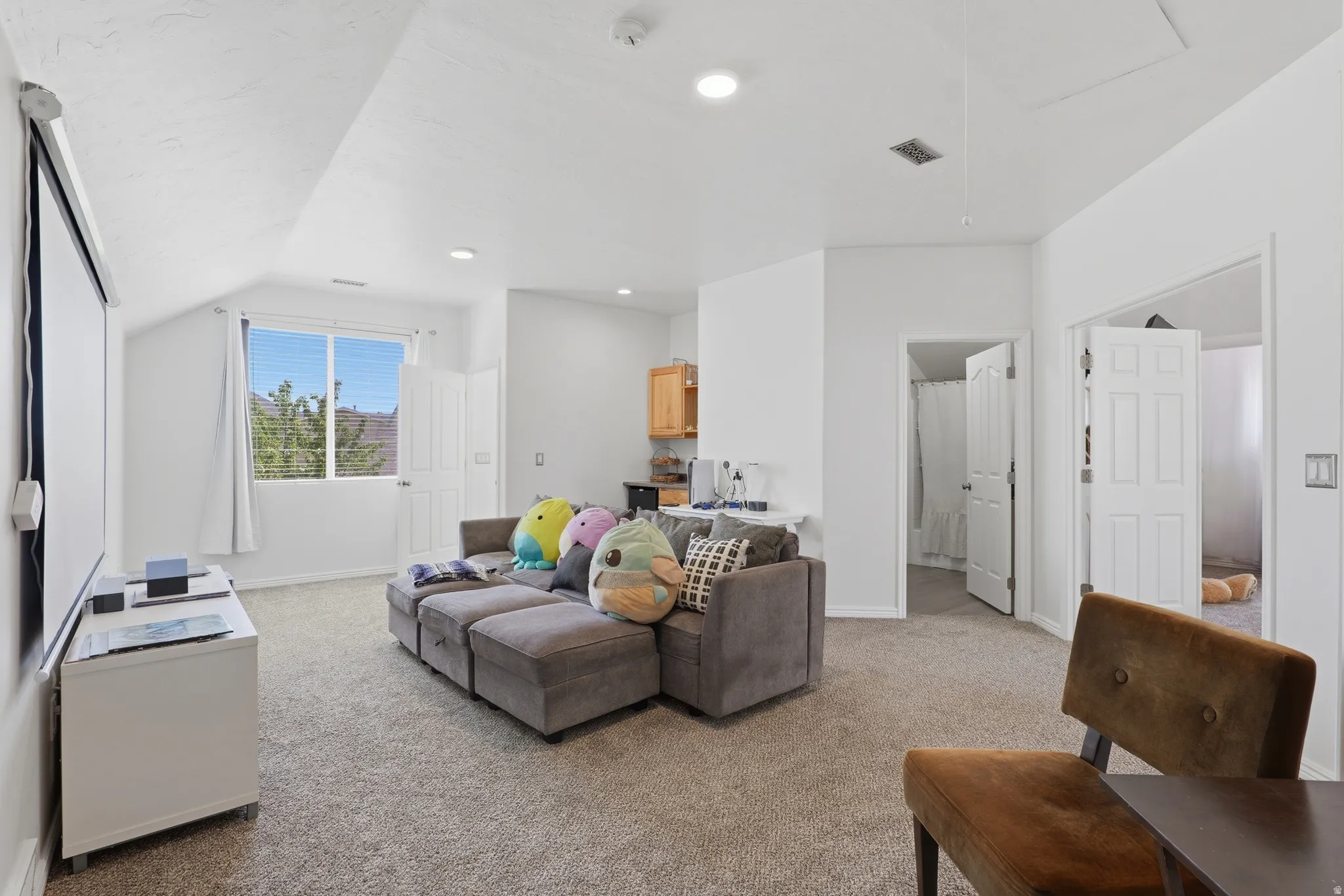 Carpeted living area featuring a window, recessed lighting, and a built-in cabinetry