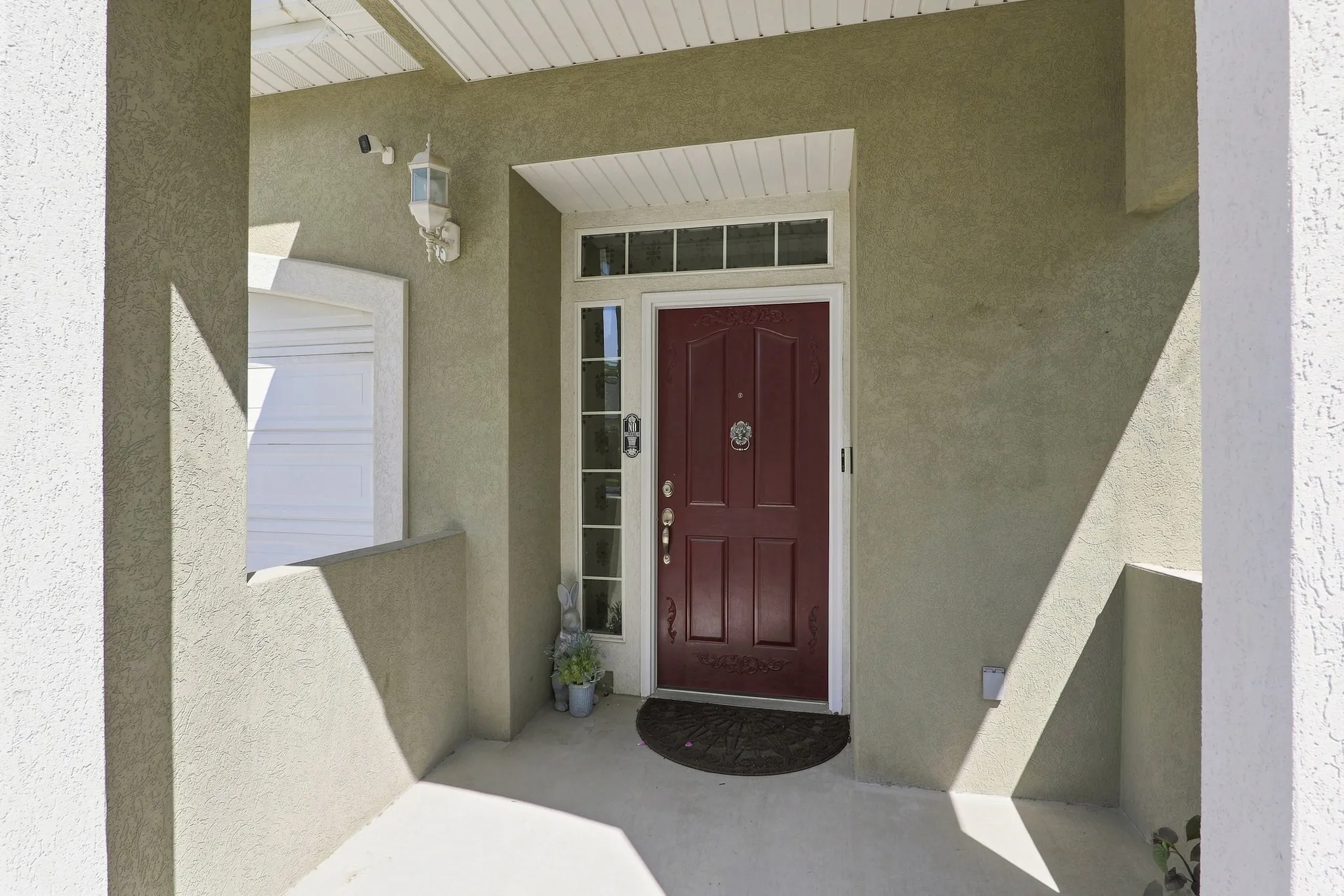 Stucco exterior with a paneled front door, transom window, and sidelight